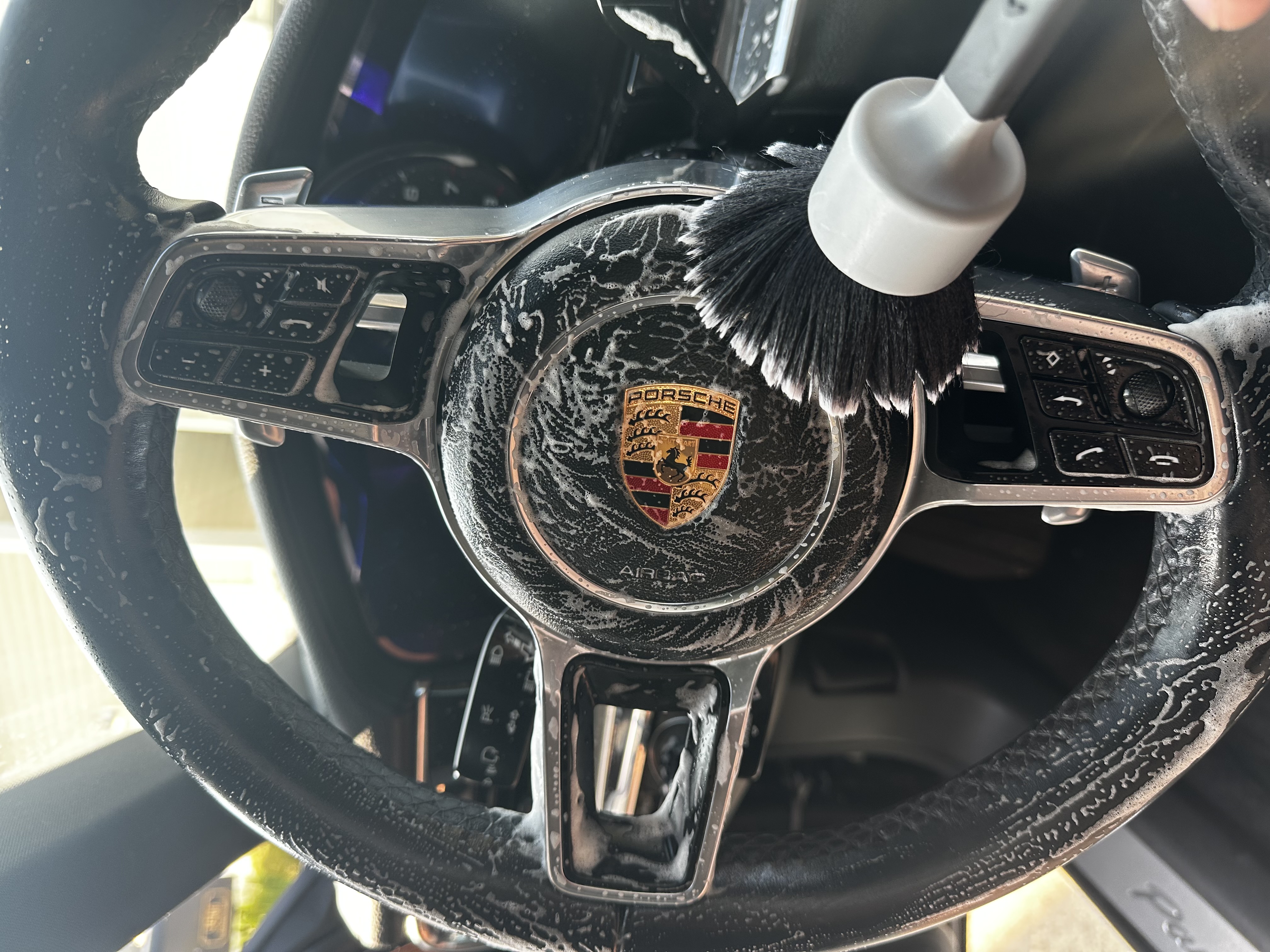 Porsche steering wheel being deep cleaned with a brush